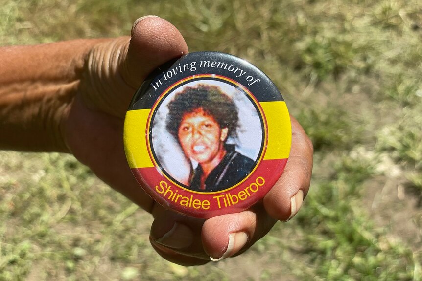 An round badge that says in loving memory of Shiralee Tilberoo, black, yellow and red background.