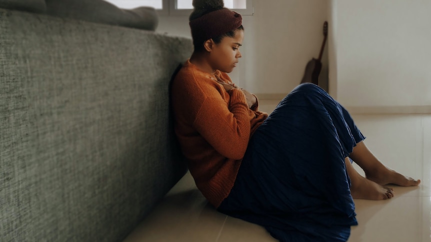 Woman looking anxious sitting beside bed 