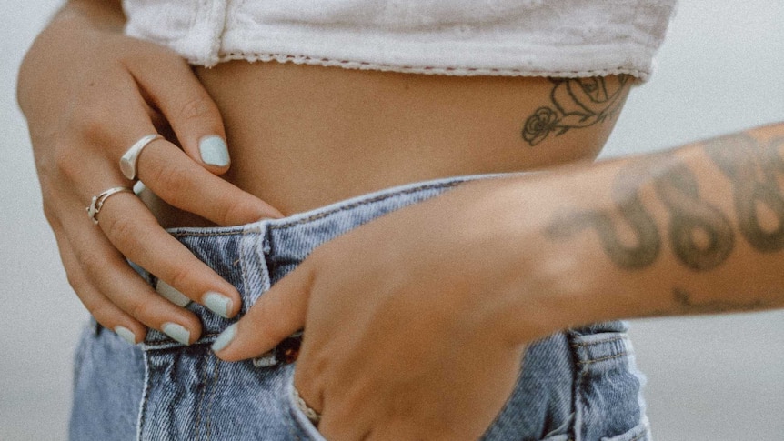 Close-up of woman's abdomen wearing jeans and white top in a story about endometriosis facts.