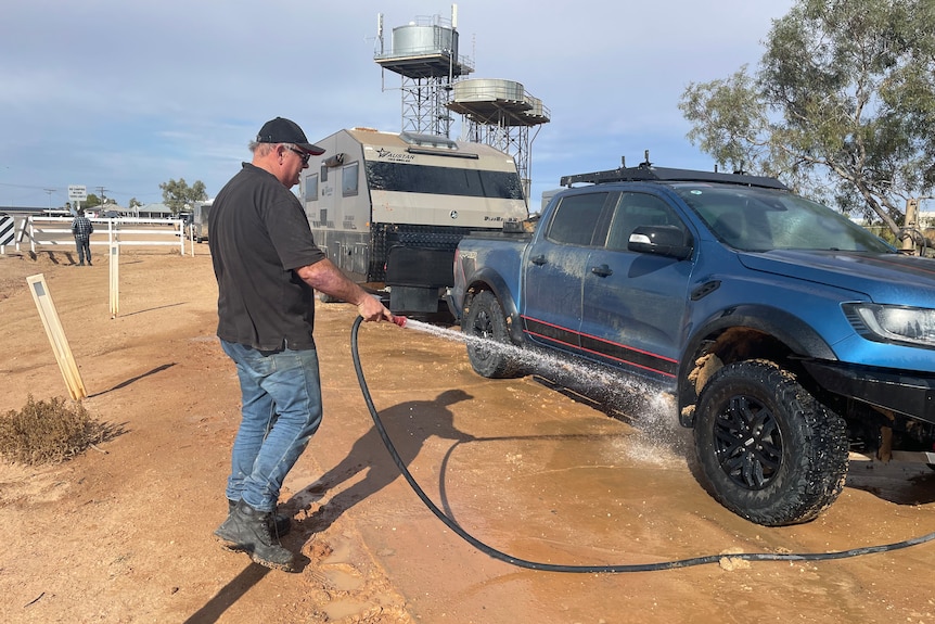 Darren Goodman washing the dirt off his vehicle after driving along Birdsville Track