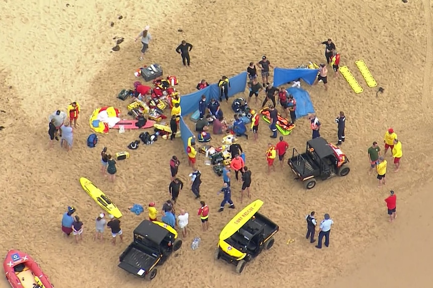 People on the beach looking after injured people after boating accident.