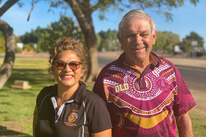 mid shot of an indgenous woman standing next to an indigenous man, both smiling with blurred background