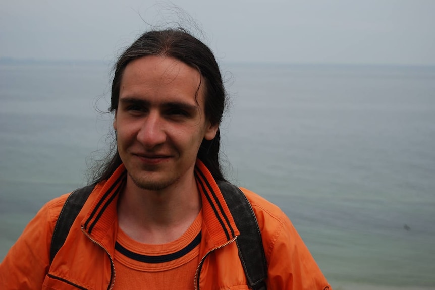 A portrait of Leonid standing in front of the sea.