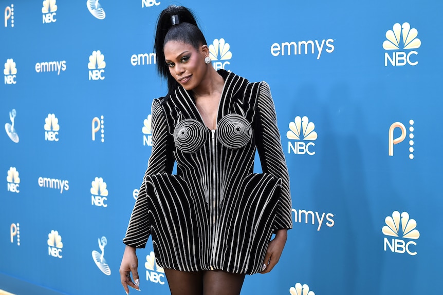 Laverne Cox in a black long-sleeved dress with silver metallic piping and structured hips