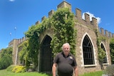 A man stands in front of a building that looks like a castle