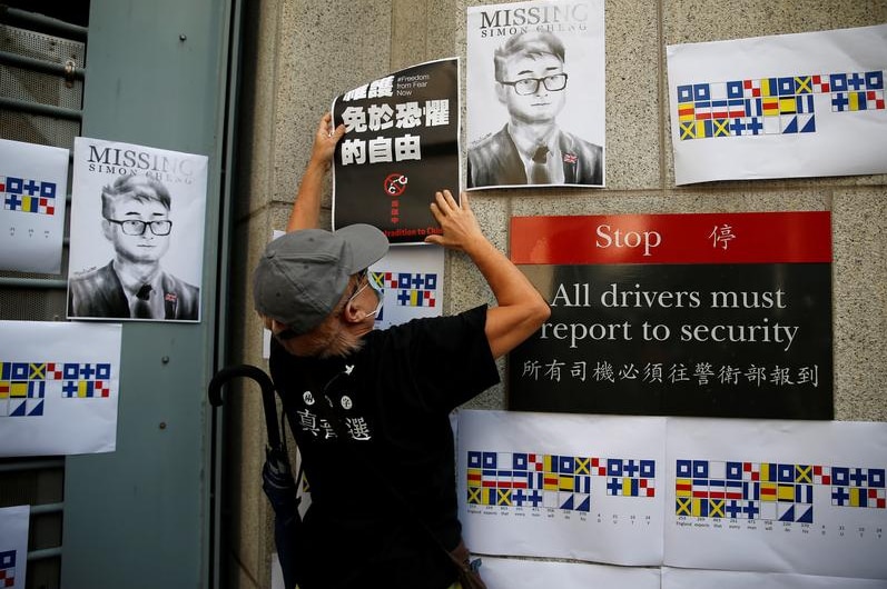 A demonstrator puts a poster on the wall of British Consulate-general office.