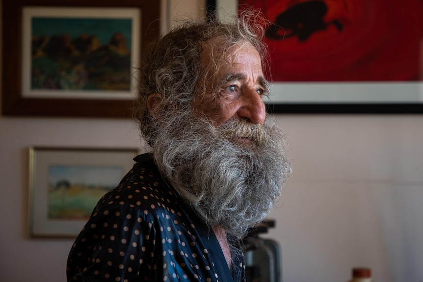 a portrait of a bushy-bearded older man indoors
