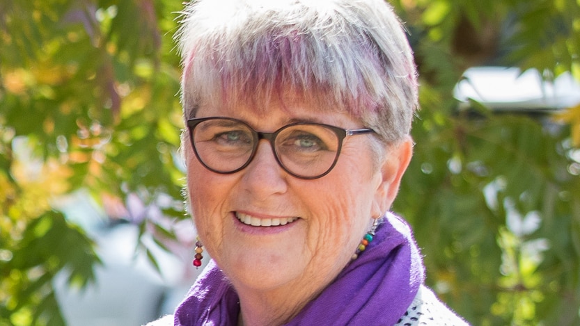 A woman with glasses smiles at the camera