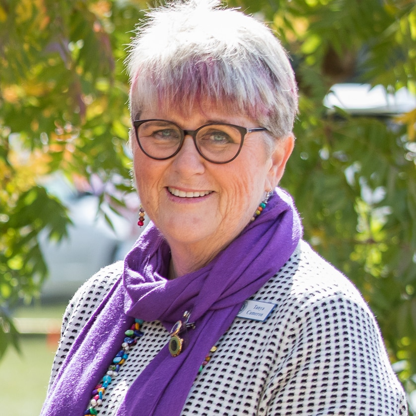 A woman with glasses smiles at the camera