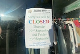 A sign for public holiday trading hours in an op shop window saying the store will be closed for Thursday and Friday