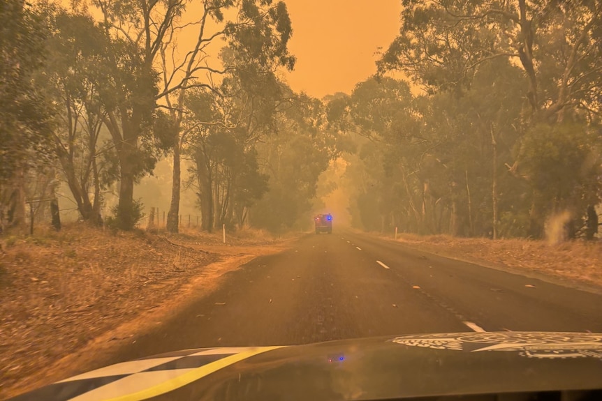 The view from the windscreen of a car, obscured by thick orange smoke.