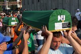 Bosnian Muslims carry caskets with the remains of their relatives