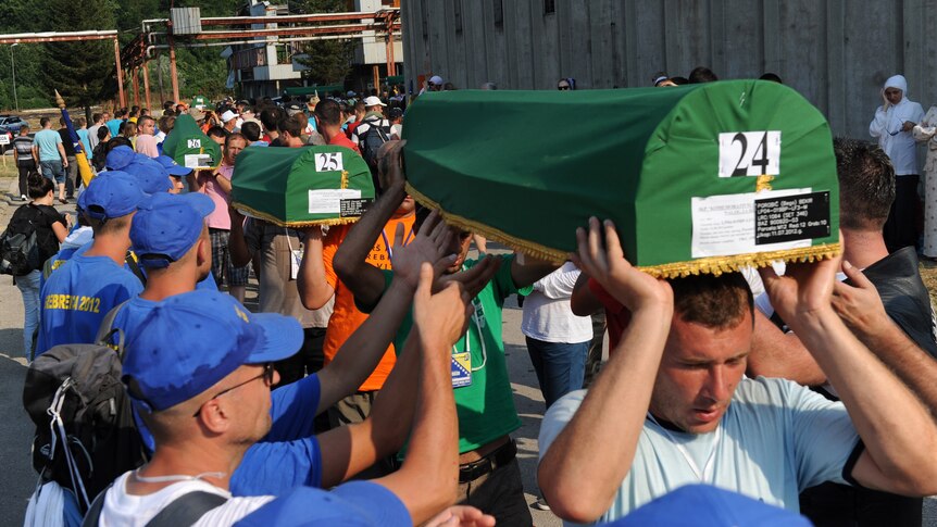 Bosnian Muslims carry caskets with the remains of their relatives