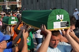 Bosnian Muslims carry caskets with the remains of their relatives