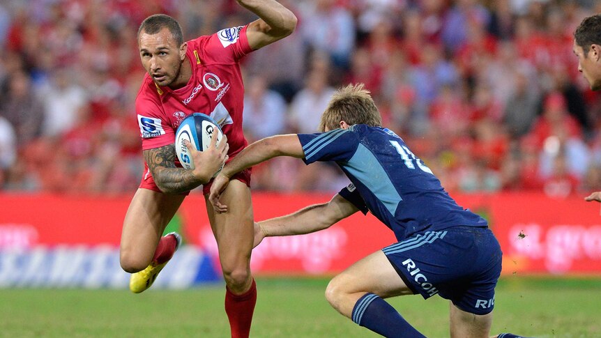 Arm wrestle ... Quade Cooper evades a Blues tackle.