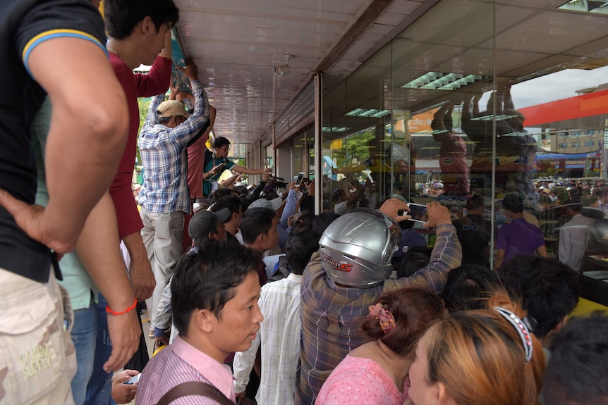 Cambodians gather at the scene of the murder of political analyst Kem Ley.