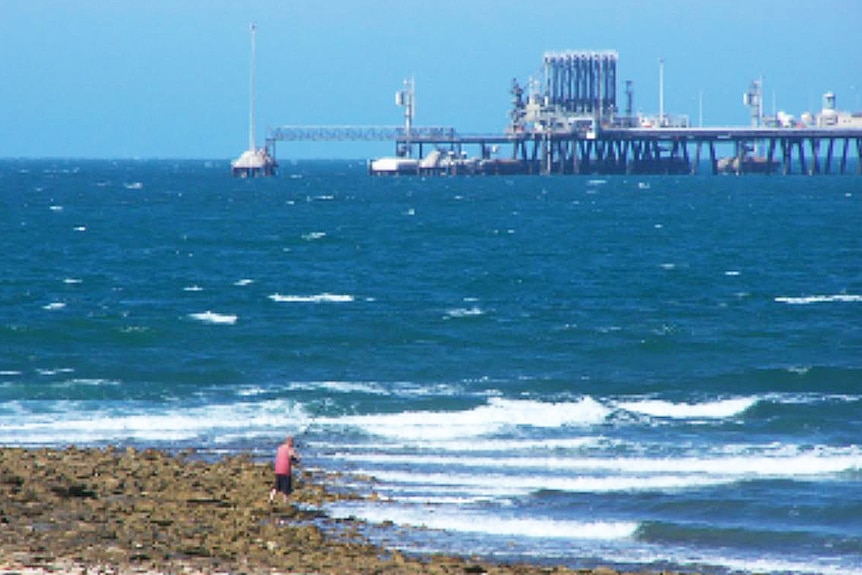 A beach with an industrial wharf behind