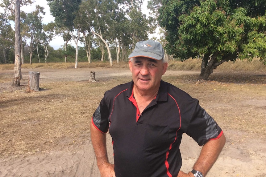 A man in a cap and polo shirt stands on a dirt patch which once was his 80-year-old fishing hut.