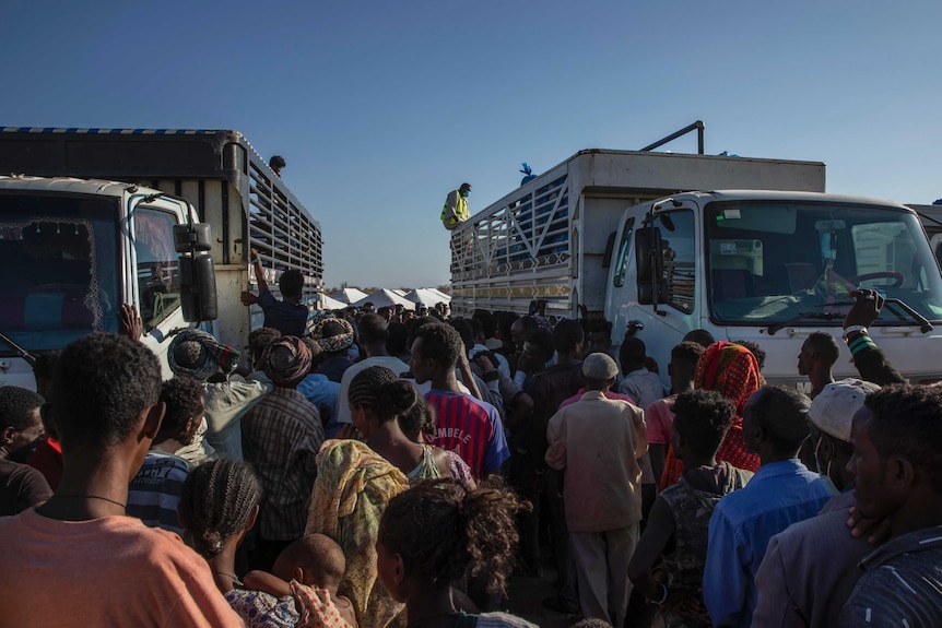 Refugees who fled conflict in Ethiopia's Tigray region wait to receive aid at a camp in Sudan