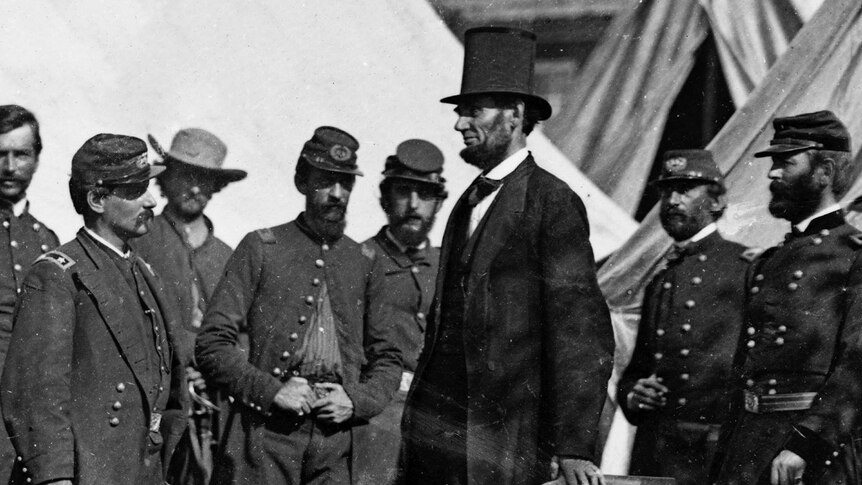 Abraham Lincoln wears a stop hat surrounded by a group of officers.