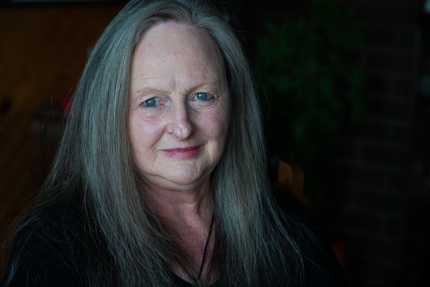 A bold portait of a woman with long hair smiling at camera.