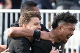 Four New Zealand All Blacks players embrace as they celebrate a try against Australia's Wallabies.