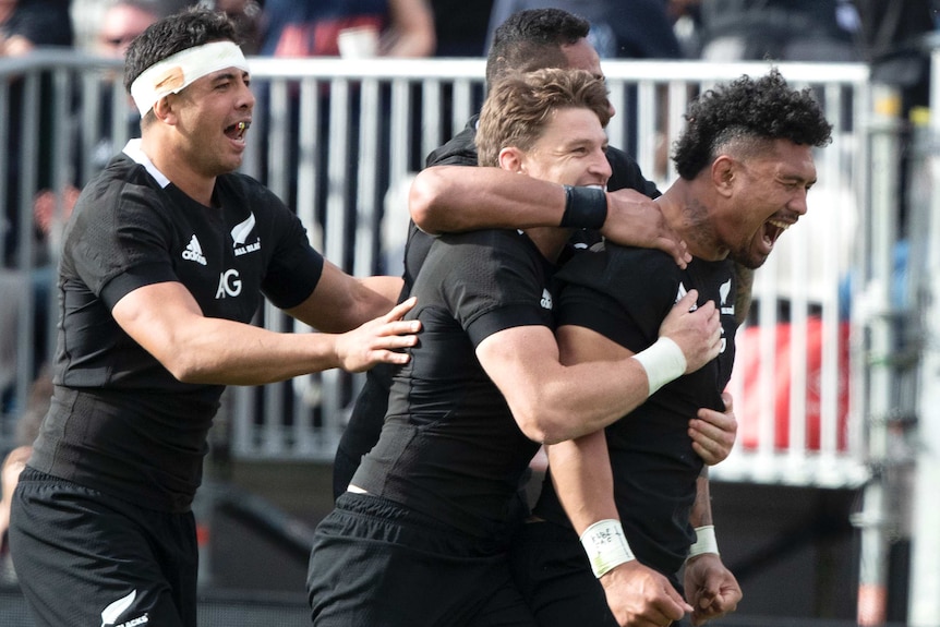 Four New Zealand All Blacks players embrace as they celebrate a try against Australia's Wallabies.