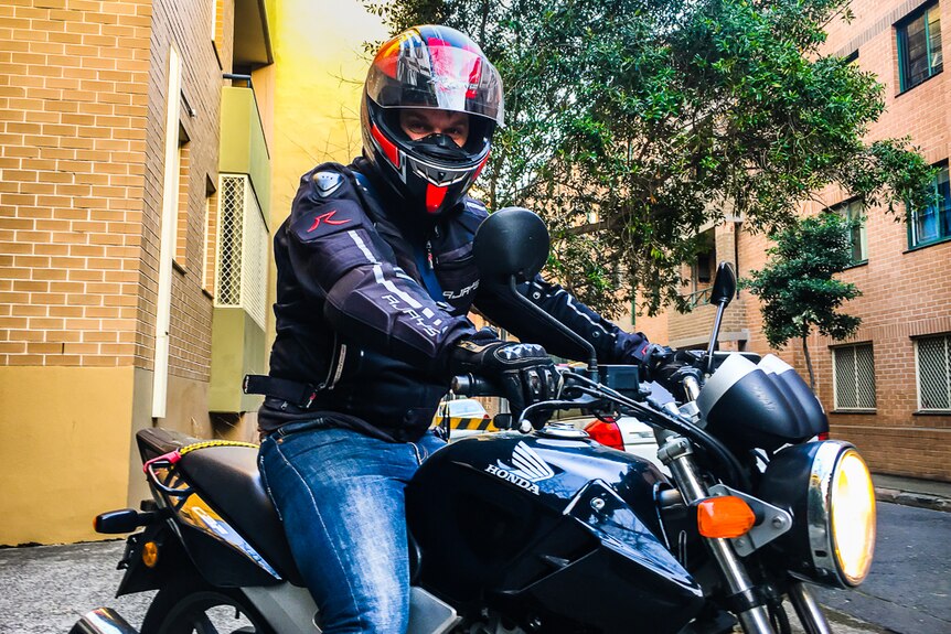 A motorcyclist wearing a helmet sitting on a bike.