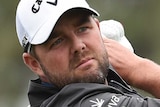 Marc Leishman holds a pose with his gold club behind him