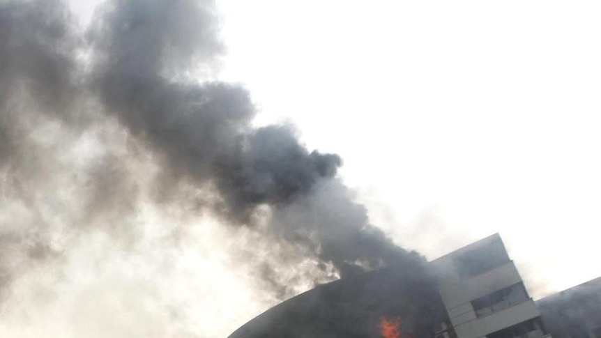 Workers point towards a burning garment factory in Ashulia, Bangladesh