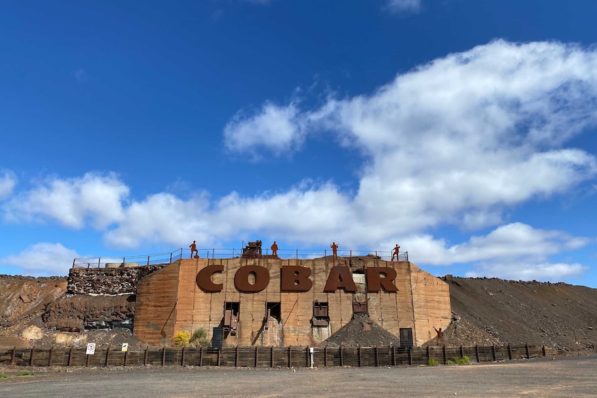 A rusted metal sign that says "Cobar", beneath a deep blue sky.