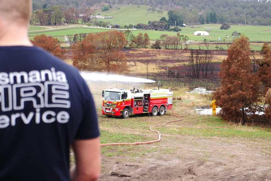 A fire truck in the distance blowing a white substance out of the top.