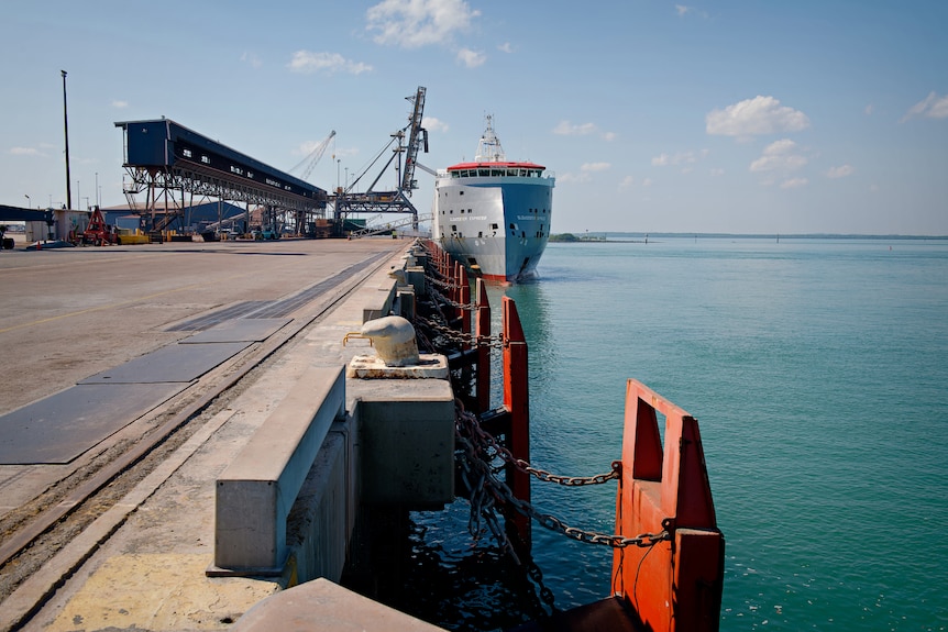 A ship anchored at a wharf part of the Darwin Port, on a sunny day.