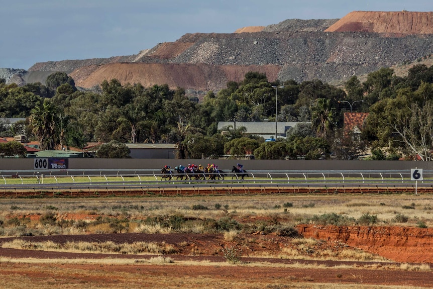 Horses running around a red-dirt track.