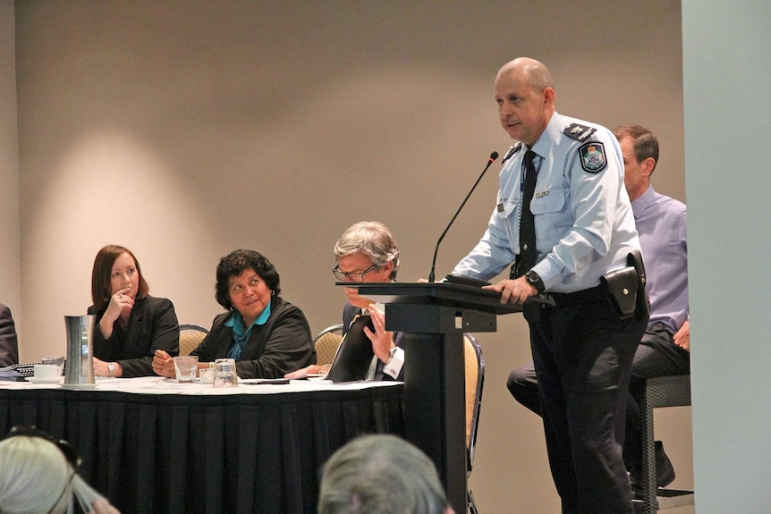 A uniformed police officer stands behind a lectern.