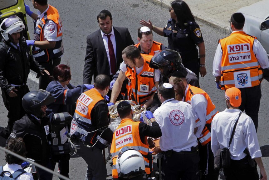 Emergency service workers carry the victim who is not visible, on a stretcher