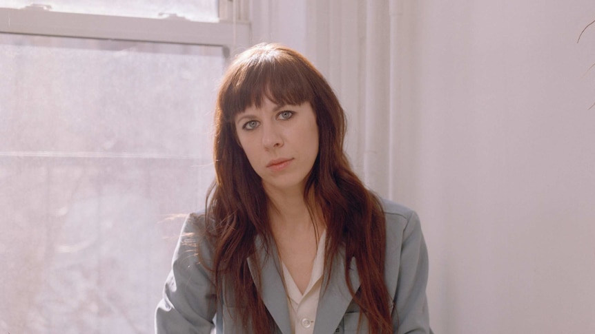 Missy Mazzoli sits by a window in a white room.