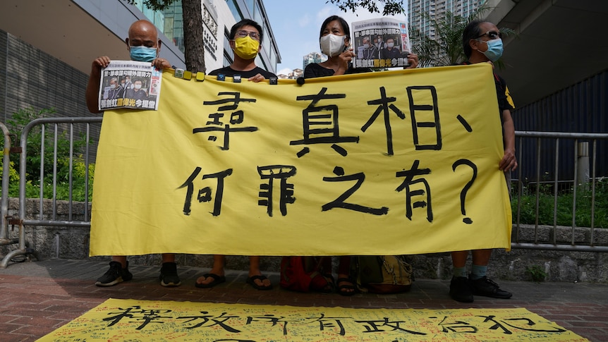 Hong Kongers hold up yellow banners outside the court where Apple Daily executives are being heard.