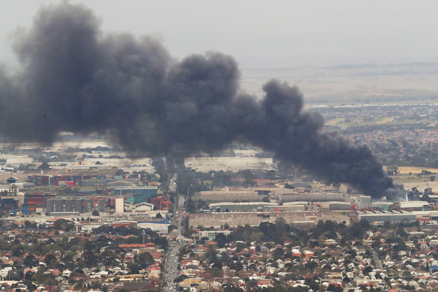 A plume of black smoke billows across the sky