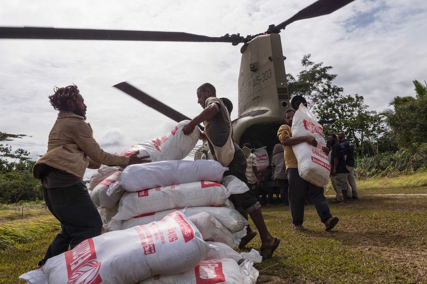 Workers unload large white sacks from a chinook helicopter in Papua New Guinea