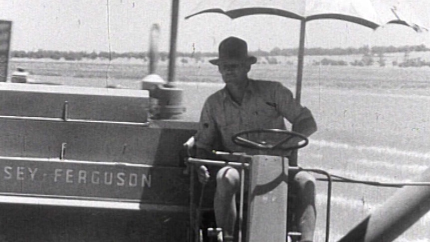 A black and white photo of a man on a wheat harvester.