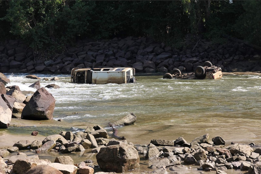 A photo of several washed away cars next to Cahill's Crossing at low tide.