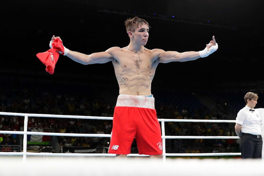 Michael Conlan stands in the boxing ring after his fight, giving the finger on both hands.