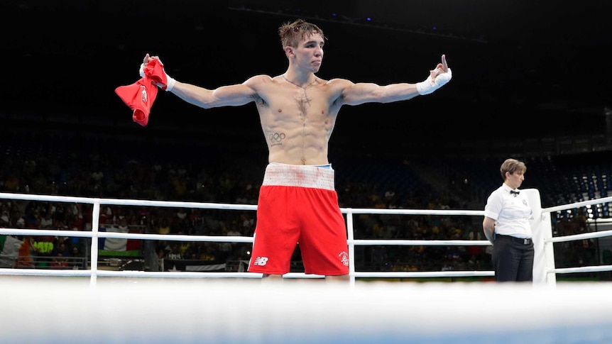 Michael Conlan stands in the boxing ring after his fight, giving the finger on both hands.