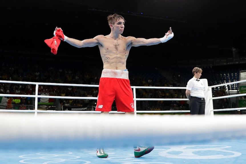 Michael Conlan stands in the boxing ring after his fight, giving the finger on both hands.