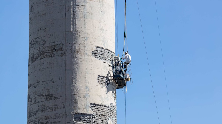 A worker repairs one of the power plant's chimneys, just one week before its closure.