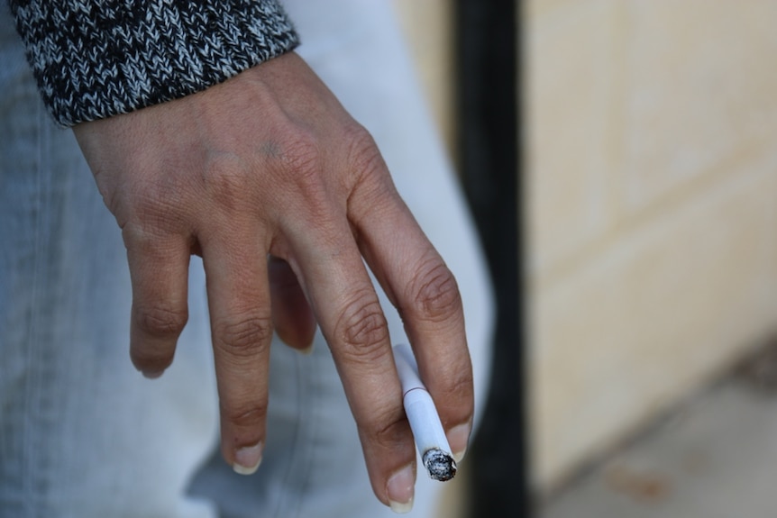Woman's hand holding a lit cigarette