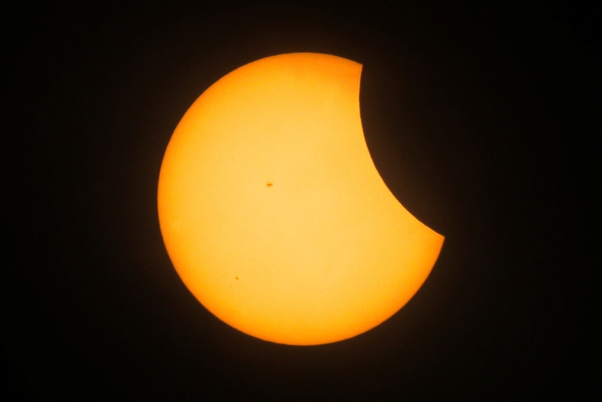 A partial solar eclipse takes place against a black sky