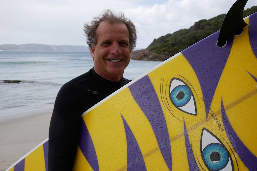 WA surfer Mike Neunuebel displays his surfboard