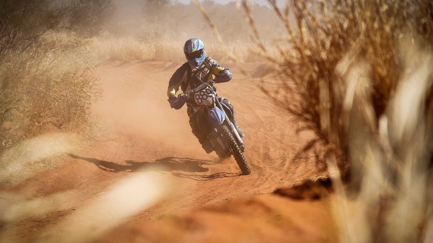 A man on a motorbike taking part in Finke Desert Race.